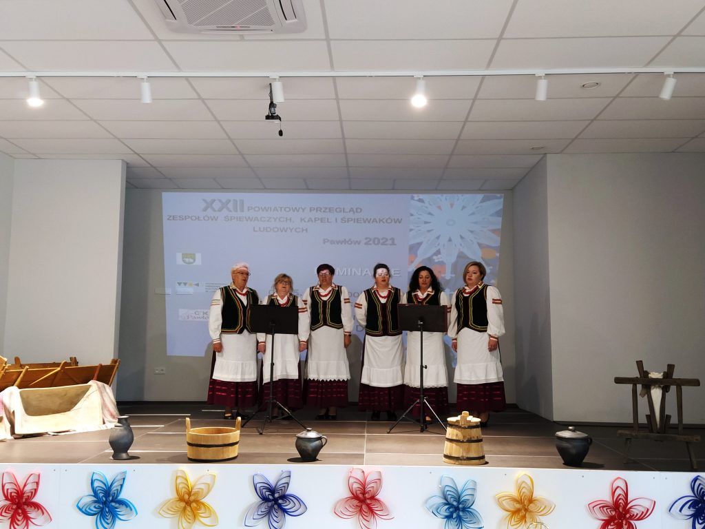 sześć kobiet na scenie śpiewających w strojach ludowych