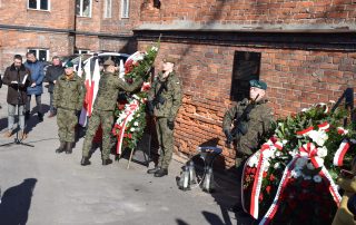 żołnierze w mundurach przy tablicy upamiętniającej zołnierzy wyklętych