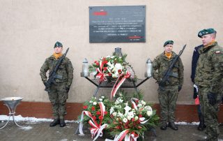 trzech żołnierzy stojących przy tablicy upamiętniającej