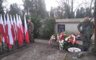 dwóch żołnierzy przy pomniku obok wieńce