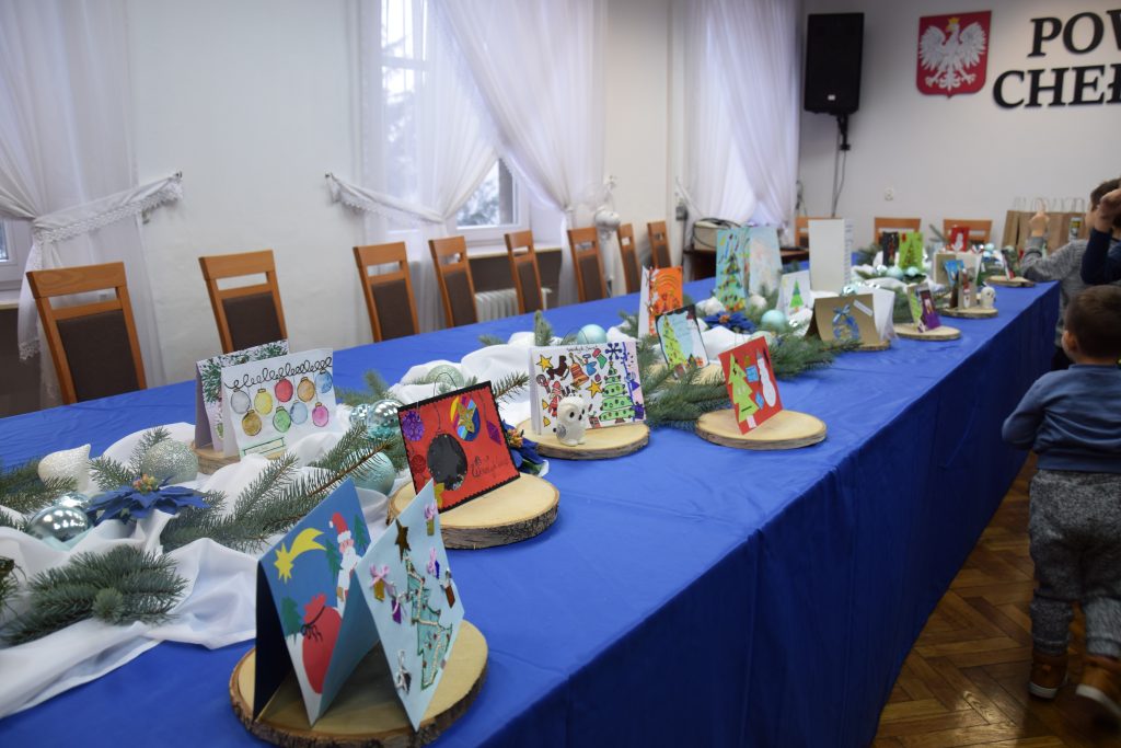 kartki bożonarodzeniowe na stole ozdobionym świerkiem i bombkami 