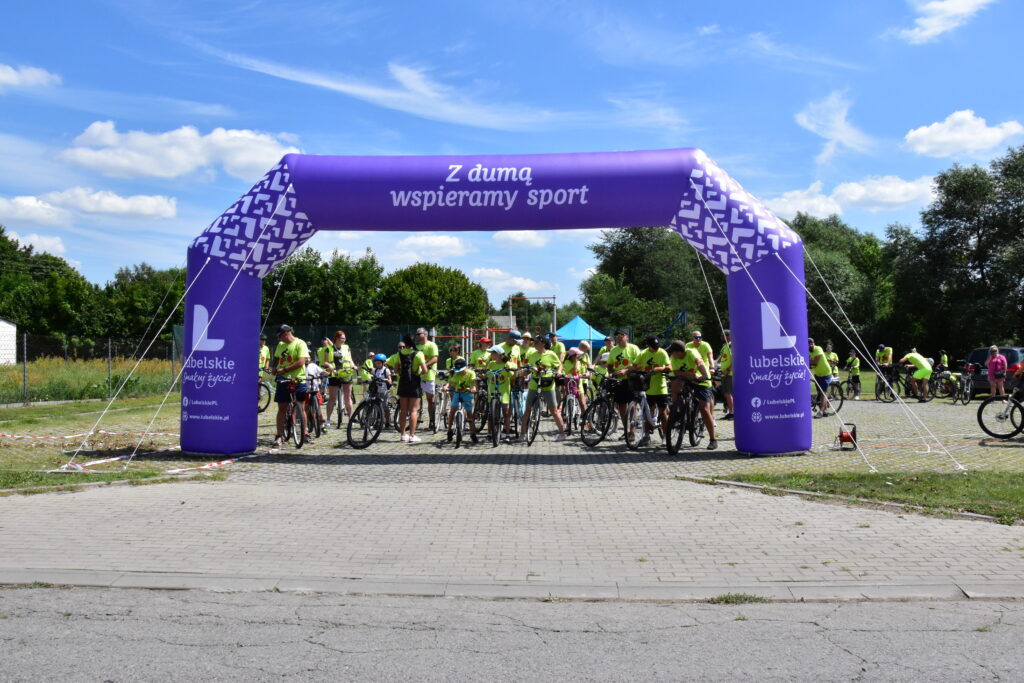 rowerzyści, dmuchana brama w kolorze fioletowym z napisem "z dumą spieramy sport"