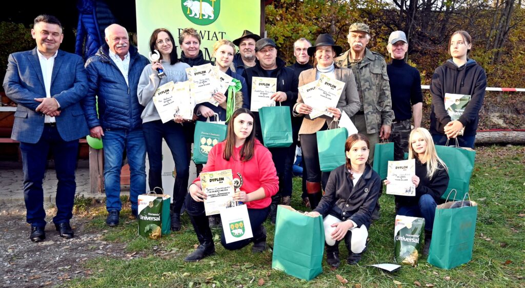 grupa osób stoją, trzy osoby klęczą, dyplomy, puchary