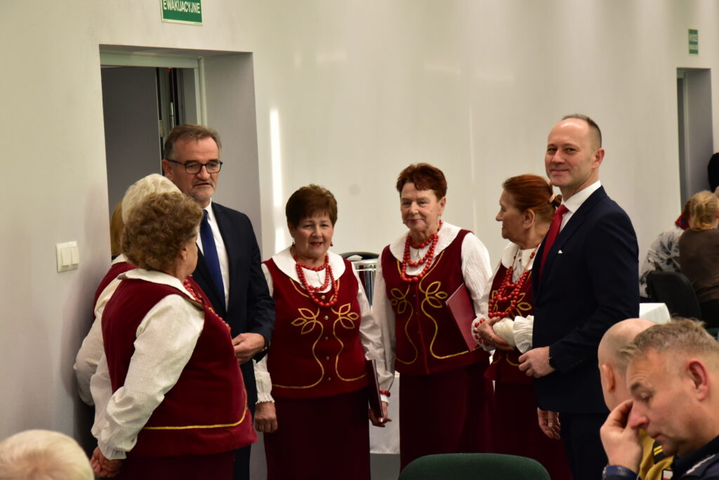 grupa osób stoją, kobiety w ludowych strojach.